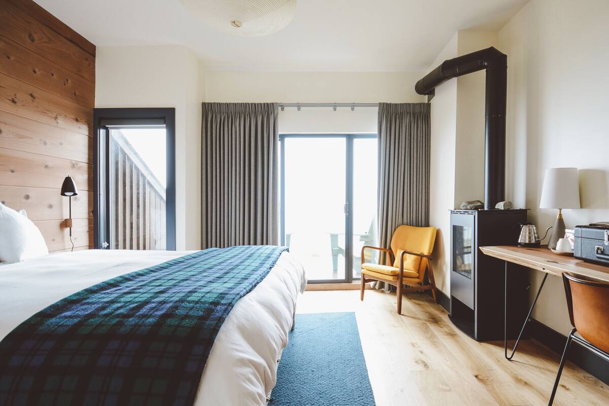 Quarto de hotel com cama, escrivaninha, cadeira, cozinha compacta e vista para o exterior.