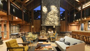 A spacious lobby with a stone fireplace, wooden furniture, and a bar area. - Timber Cove Resort (Jenner)