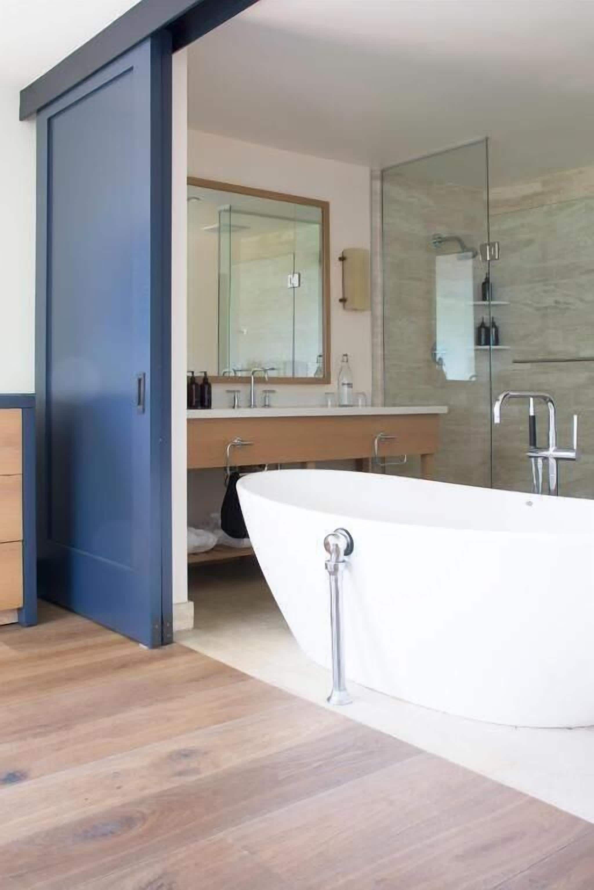 A modern bathroom with a freestanding bathtub, a large mirror, and a glass shower enclosure.