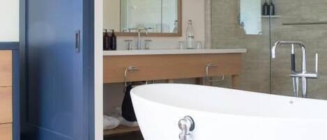 A modern bathroom with a freestanding bathtub, a large mirror, and a glass shower enclosure.