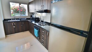 Cozinha moderna com armários de madeira escura, eletrodomésticos de aço inoxidável e janela com vista para um jardim.