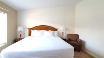 Una habitación de hotel con una cama grande, dos lámparas de noche, una silla y un ventanal.