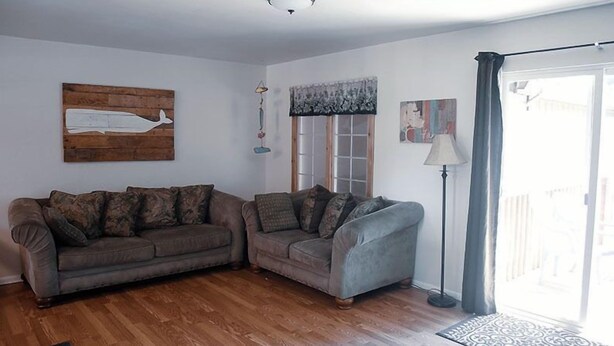 A living room with two sofas, a wooden floor, a window with curtains, and a lamp. - 3 Rivers Resort and Guide Service (Forks)