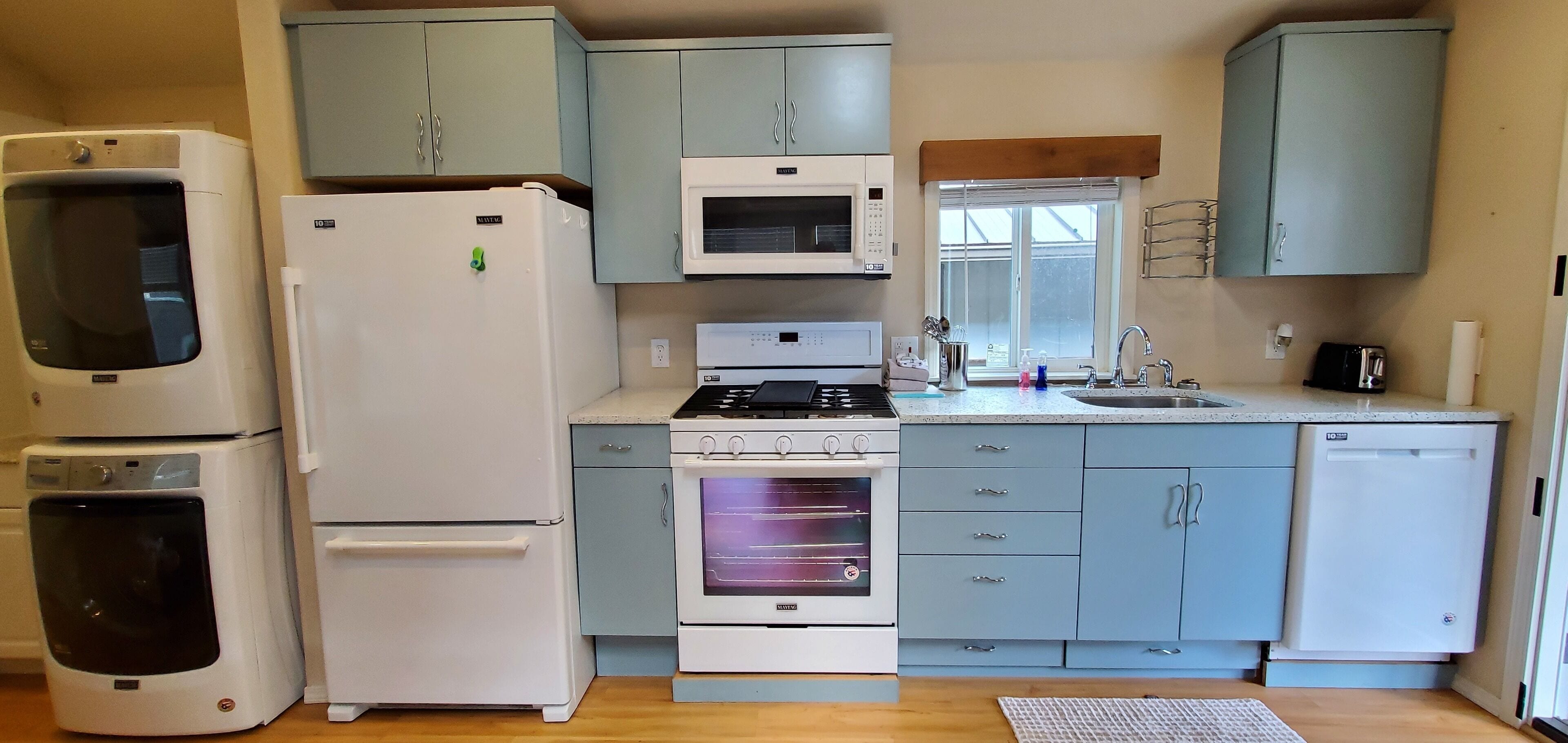 A compact kitchen with a refrigerator, microwave, stove, oven, and sink.
