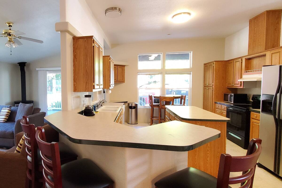 A modern kitchen with wooden cabinets, a central island, and a dining area with a sofa and chairs.