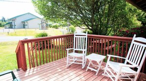 A wooden deck with two rocking chairs and a small table.