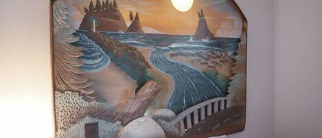 A mural with a coastal scene, including a lighthouse, waves, and a bridge.