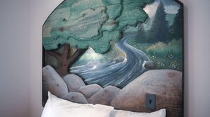 A wall-mounted artwork depicting a river flowing through a mountainous landscape with rocks and trees.