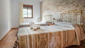 Une chambre d’hôtel avec deux lits, un mur en briques, une fenêtre avec des rideaux et un radiateur.
