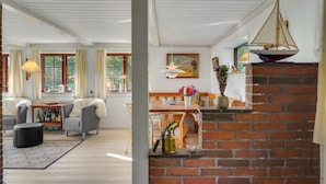 A cozy living room with a fireplace, a dining area, and a view of the outdoors through large windows.