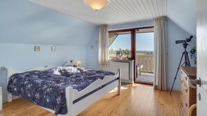 A bedroom with a bed, a desk with a telescope, and a balcony with a view.
