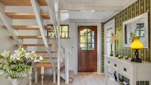 A staircase with wooden steps leading to a landing, a white console table with decorative items, and a door with a window.