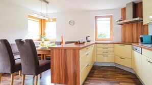 Eine kleine Küche mit Holzausstattung, einem Essbereich mit Stühlen und einem Fenster für natürliches Licht.