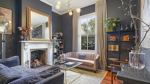 A living room with a fireplace, a sofa, a coffee table, and a bookshelf. - Tropical Paradise -Pool - Spa - Spacious (Auckland)