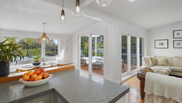 A modern kitchen with a granite countertop, a bowl of fruit, and pendant lighting. - Tropical Paradise -Pool - Spa - Spacious (Auckland)