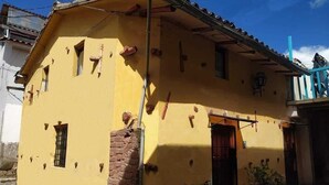 Ein gelbes Gebäude mit einem Ziegeldach, einer Backsteinmauer und einem kleinen Fenster.