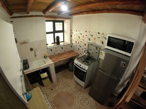 A compact kitchen with a gas stove, microwave, and a small sink.