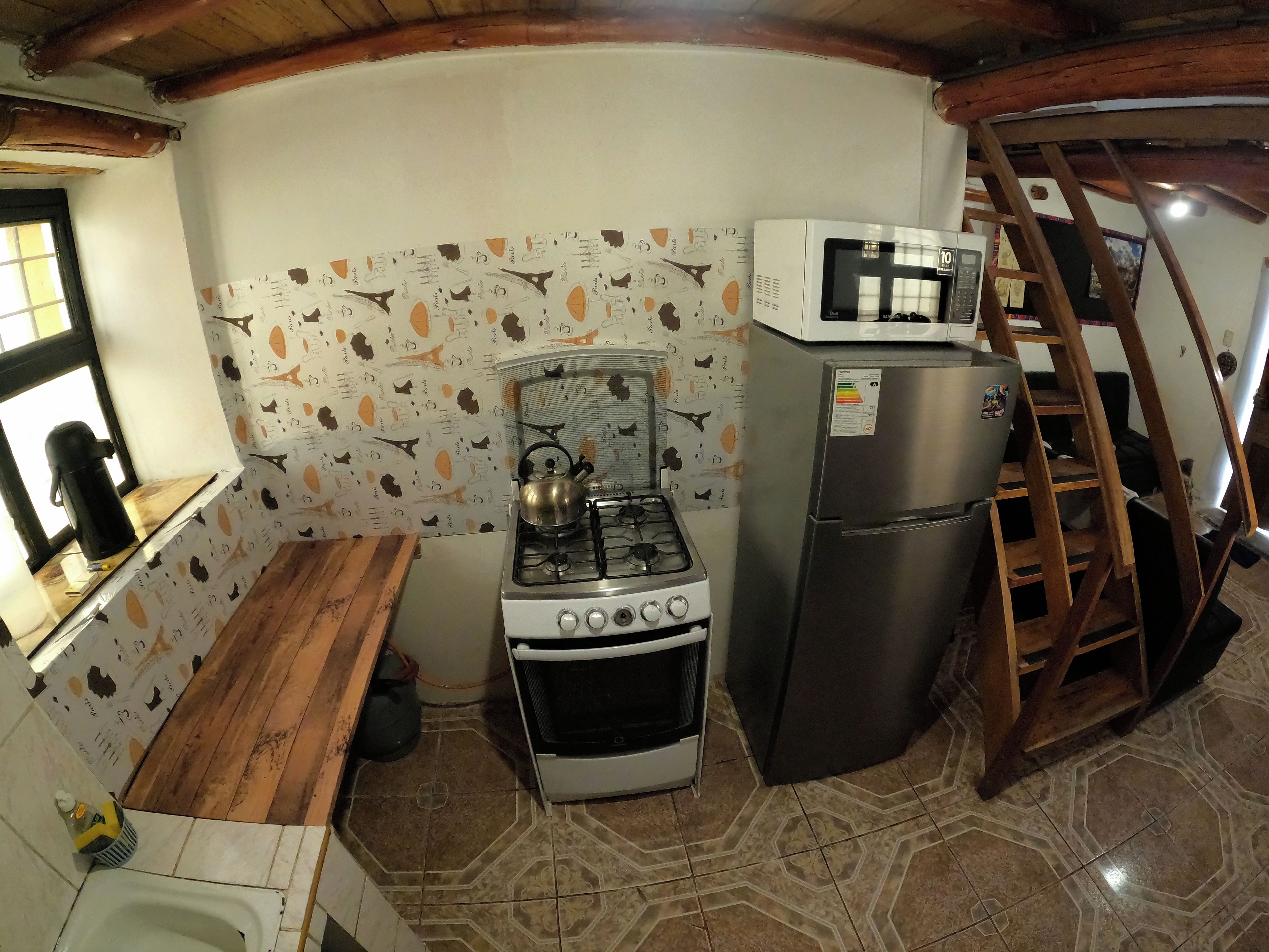 Une cuisine compacte équipée d’une cuisinière à gaz, d’un four à micro-ondes et d’un réfrigérateur.