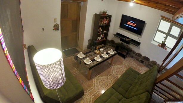 Ein gemütliches Wohnzimmer mit Fernseher, einer Couch, einem Couchtisch und einer Lampe.