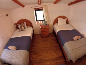 A room with two single beds, wooden headboards, a small bedside table with a lamp, and a window with curtains. - SUMAQ WASI (Cusco)