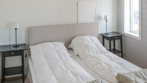 A neatly made bed with a white duvet and pillows, two bedside tables with lamps, and a window with a view of the outside. - 5 bedroom nice home in Borhaug (Borhaug)