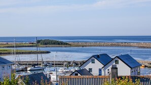 A marina with boats docked, a rocky breakwater, and houses with blue roofs. - 5 bedroom nice home in Borhaug (Borhaug)