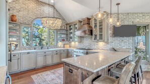 Una cocina amplia con una isla grande, electrodomésticos integrados y una pared decorativa de ladrillo.