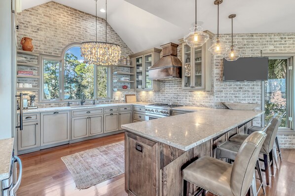 Una cocina amplia con una isla grande, electrodomésticos integrados y una pared decorativa de ladrillo.