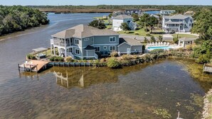 A waterfront property with a large house, a dock, and a swimming pool. - Summer Baycation | Waterfront | Private Pool, Hot Tub (Virginia Beach)