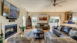 A spacious living room with a fireplace, comfortable seating, a television, and a ceiling fan. - Summer Baycation | Waterfront | Private Pool, Hot Tub (Virginia Beach)