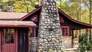 A stone chimney, a red door, and a wooden bench. - Charming Cottage in the Heart of the Shawangunks (Wallkill)