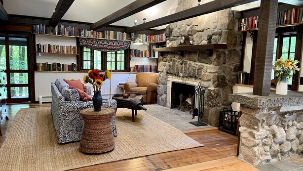 A cozy living room with a fireplace, bookshelves, a patterned sofa, and a coffee table. - Charming Cottage in the Heart of the Shawangunks (Wallkill)
