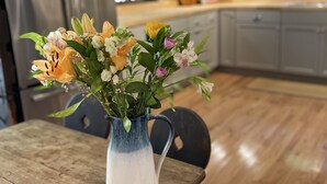 A dining table with a vase of flowers in the center. - Charming Cottage in the Heart of the Shawangunks (Wallkill)