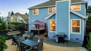 A blue house with a patio area featuring a grill, outdoor seating, and a fire pit. - Updated 5 BR house w/ hot tub - 5 min walk to downtown! (Geyserville)