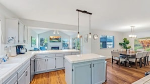 A modern kitchen with white cabinets, a wooden floor, and pendant lighting. - Updated 5 BR house w/ hot tub - 5 min walk to downtown! (Geyserville)