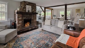 Una sala de estar con chimenea de ladrillo, alfombra estampada y un sofá.