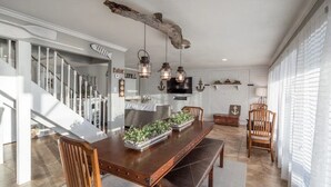 A modern kitchen with a wooden dining table, hanging lanterns, and a staircase.