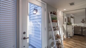 A hallway with a white door, a white ladder shelf, and a white cabinet.