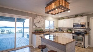 A kitchen with a large island, stainless steel appliances, and a view to the outside.