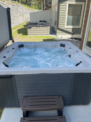 Relax in a hot tub surrounded by a deck and a stone wall.