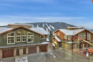 Houses with unique architectural styles stand amidst snow-covered mountains.