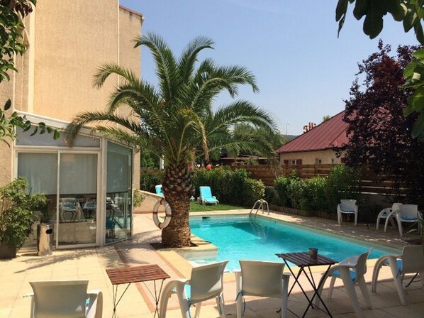 Relax by the pool surrounded by palm trees and lounge chairs.