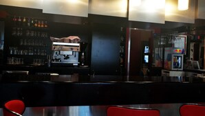 Zona de bar con una máquina de café, estantes con vasos y refrigeradores de Red Bull.