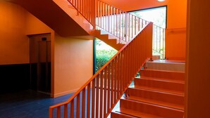 Eine Treppe mit roter Geländer führt zu einer oberen Etage.