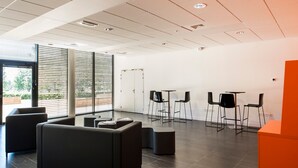 Ein moderner Arbeitsbereich mit dunklem Holzboden, schwarzen Sofas und einer leuchtend orangefarbenen Wand.