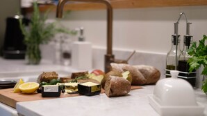 A kitchen counter with various food items, including cheese, bread, and a lemon. - Henry Matthews Apartment (Dunedin)