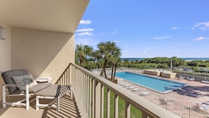 A balcony with a pool view, lounge chairs, and a clear sky. - Cape Canaveral Condo W/ Direct Ocean Views, Steps to Beach, & Pool Access! ☀️ (Cape Canaveral)