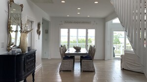 A spacious dining area with a high ceiling and a view to the outside. - Sunset, sunrise, golf cart, kayak, paddle board, launch, pet friendly & fenced. (Emerald Isle)