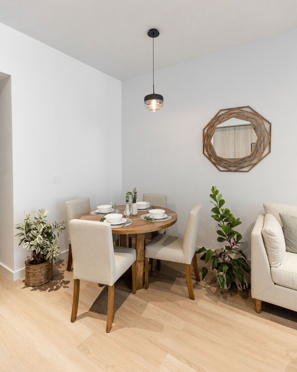 Comedor con una mesa redonda de madera, seis sillas y una lámpara colgante.