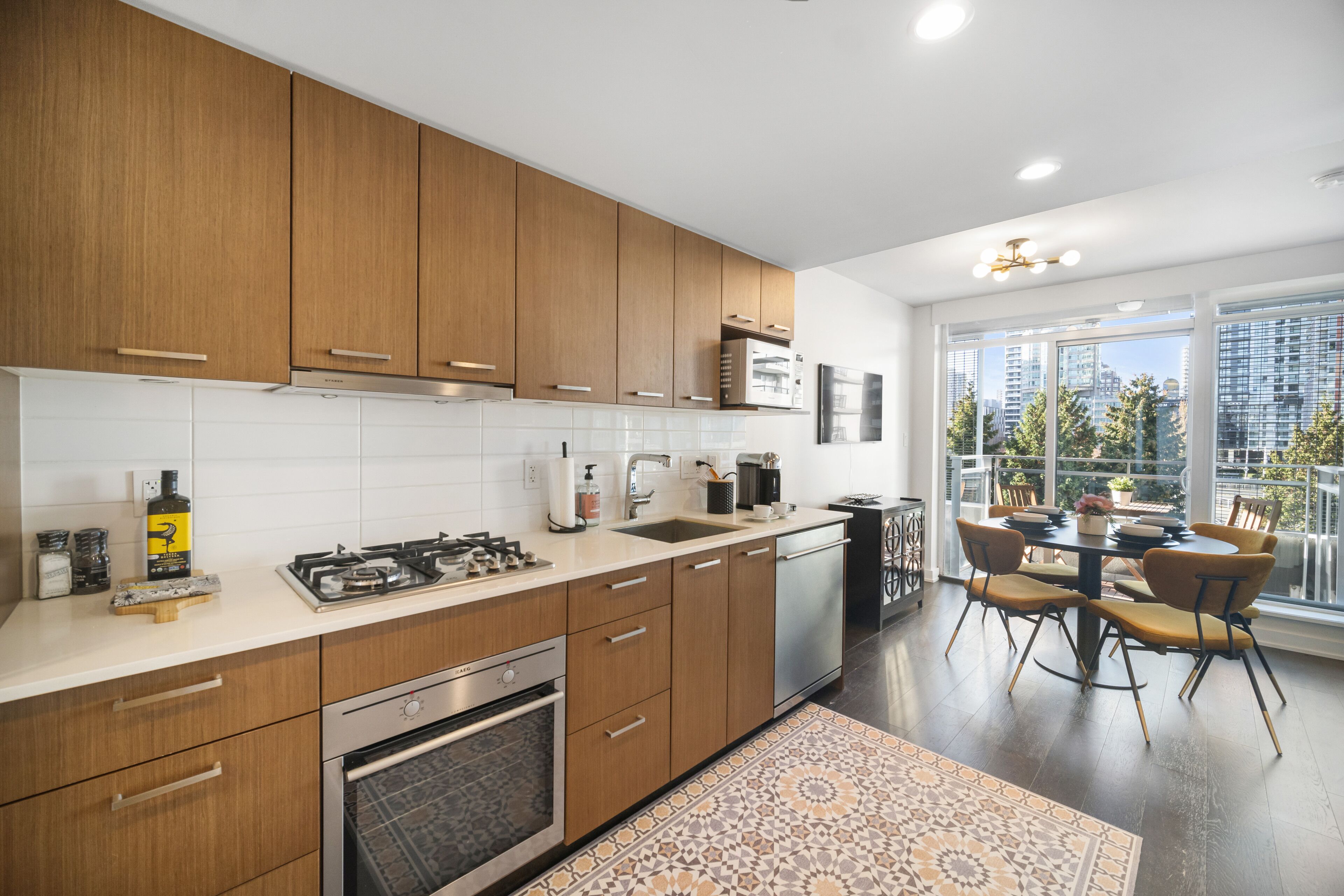 A modern kitchen with wooden cabinets, stainless steel appliances, and a dining area with a table and chairs.